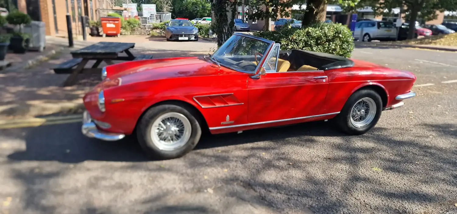 Side shot of a classic bright red Ferrari, looking polished after coming in for detailing